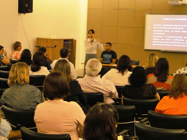 Coordenadora de Apoio às Redes de Ensino do FNDE Ana Carolina utilizando um projetor como recurso, palestrando em um auditório 